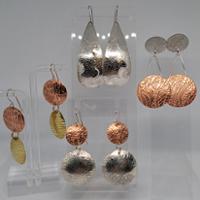 four examples of enameling work including a pendant and earrings