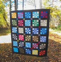 A colorful quilt hangs outdoors