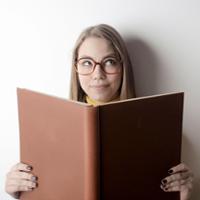 A woman with an inquisitive expression reads an oversized book