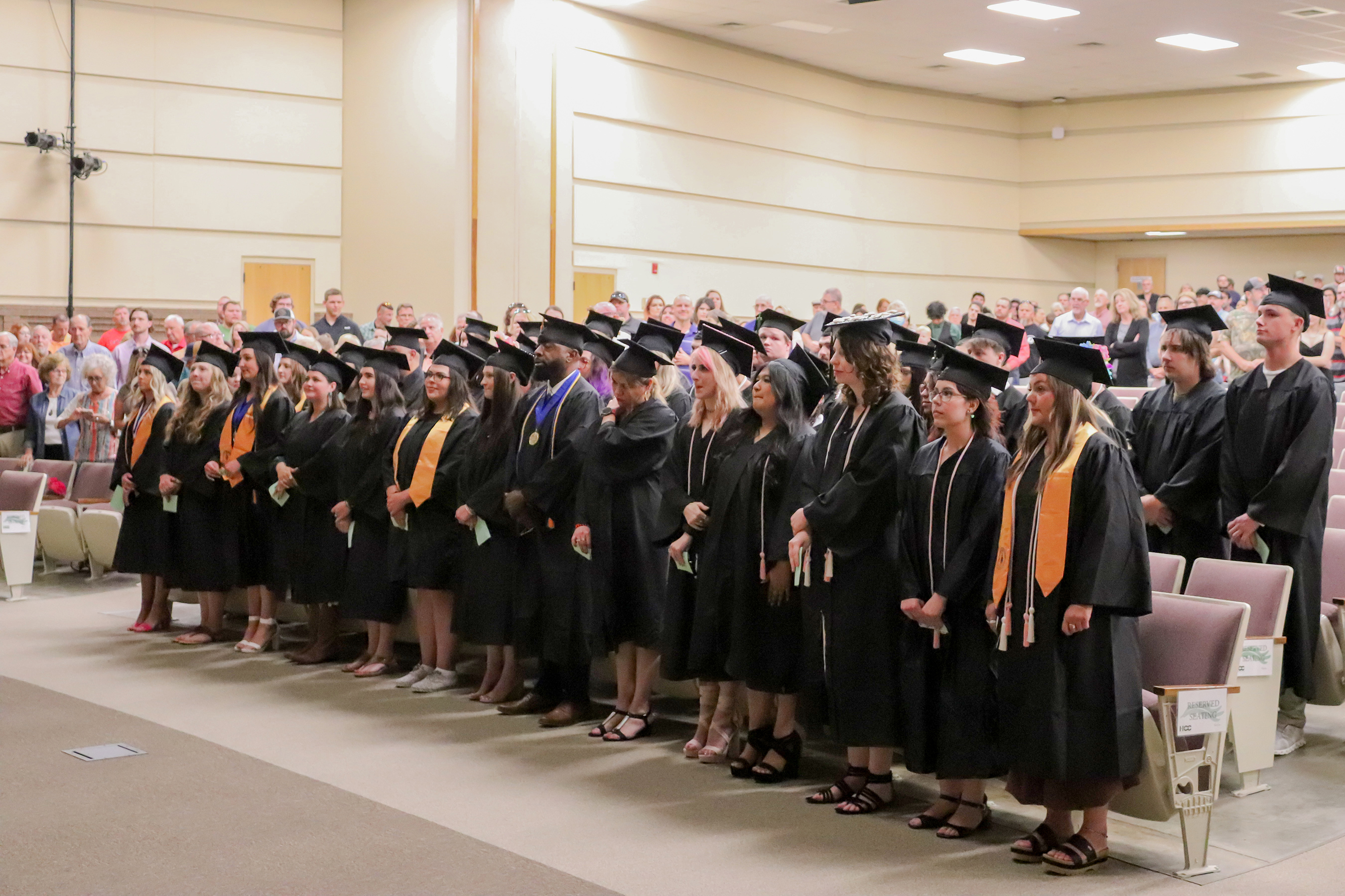 graduates standing up in their rows at a ceremony