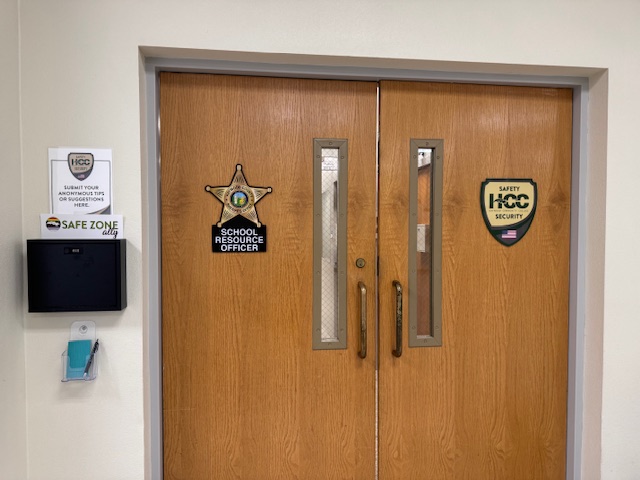 black security tip box located to the left of brown double doors leading from the auditorium lobby to the safety and security offices in the hemlock building.